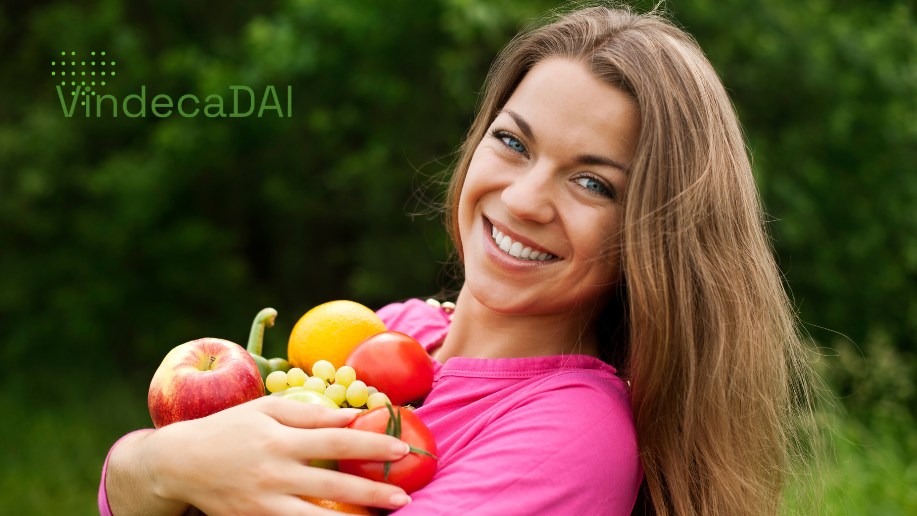 fată cu tricou roz care zâmbește la cameră cu fructe și legume în brațe vindecadai