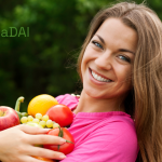 fata cu tricou roz care zambeste la camera cu fructe si legume in brate vindecadai